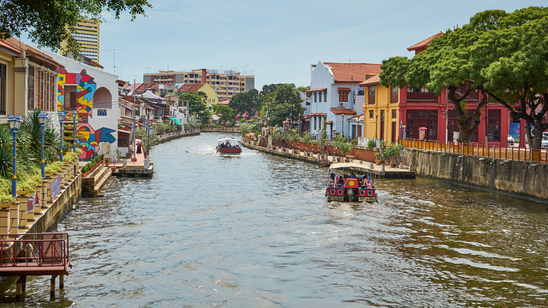 Boats sailing along river in Malacca city, Malaysia