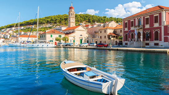 Sunny harbour with colourful church and houses in Pucisca, Croatia