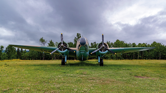 A Lockheed Hudson Bomber rests in an open field under a gloomy sky at the North Atlantic Aviation Museum in Gander, Newfoundland.